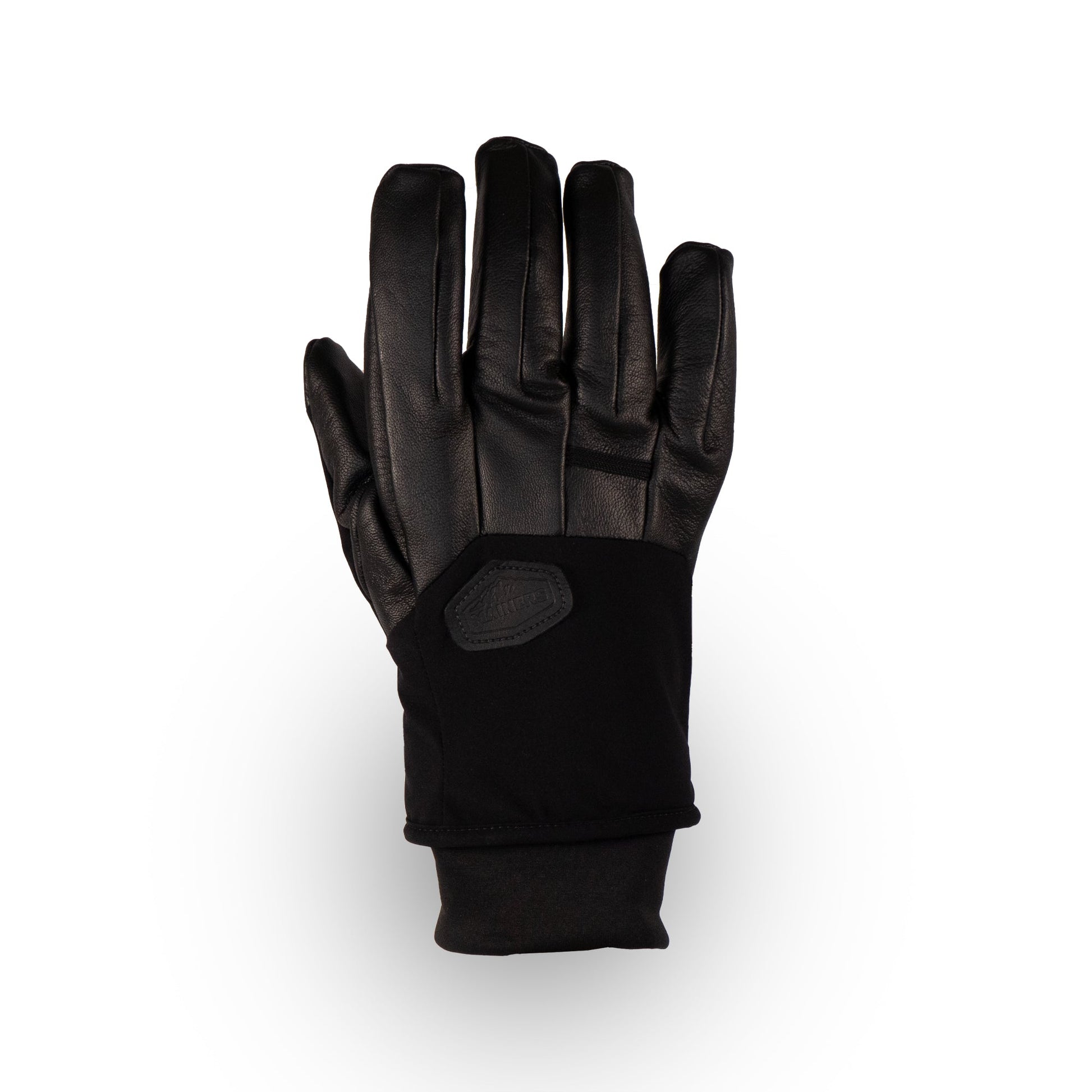 The Loaf Glove by Mainers, made from black leather, is artistically showcased with its fingers outstretched against a pristine white backdrop, offering both protection and warmth.