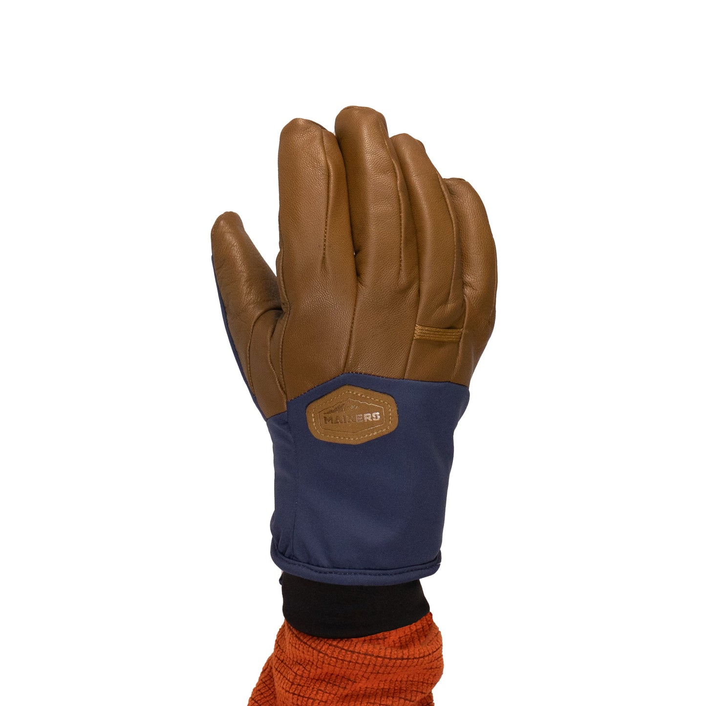 A hand adorned with the Mainers Loaf Glove, a design that combines brown leather with a blue fabric section and features a logo patch, stands out against the white background.