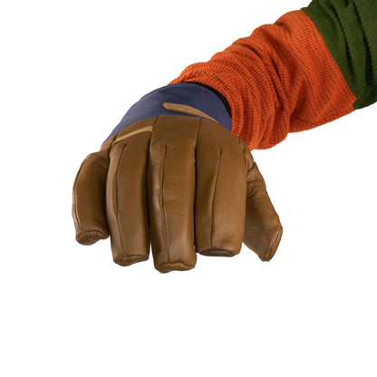 A person is wearing the Loaf Glove by Mainers, recognized for its warmth, featuring a brown leather exterior and fabric cuff, teamed with an orange and green long-sleeve shirt.